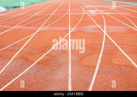 La pista rossa brillante intreccia la traiettoria bianca diritta con la traiettoria bianca curva. Foto Stock