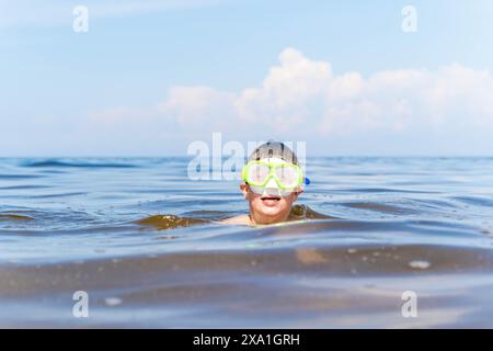 Un ragazzo nuota nell'oceano indossando una maschera subacquea. Foto Stock