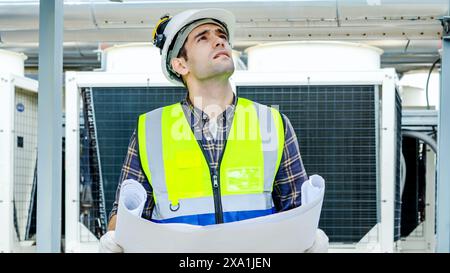 Un uomo che lavora in un cantiere, indossa un casco protettivo e un'uniforme Foto Stock