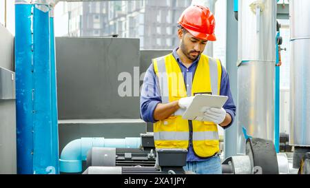 Un uomo con un tablet davanti a tubi industriali. Foto Stock