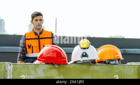 Un operaio edile che guarda cappelli rigidi colorati. Foto Stock