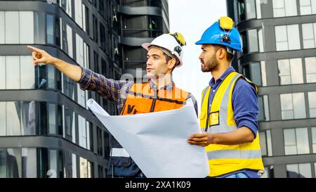 I due uomini che esaminano i progetti per i materiali da costruzione su un tetto. Foto Stock