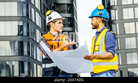 I due uomini che esaminano i progetti per i materiali da costruzione su un tetto. Foto Stock