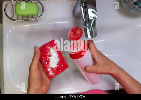 Una persona che pulisce un lavandino del bagno. Foto Stock