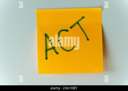 Una nota adesiva gialla su un frigorifero bianco con la parola ACT scritta in verde. Foto Stock