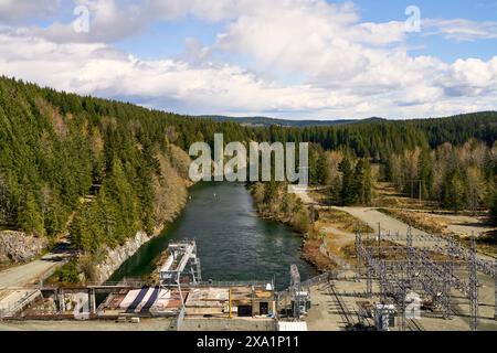 Vista dalla BC Hydro, dalla diga di Strathcona che guarda verso il basso l'infrastruttura visibile e il fiume Campbell in una giornata luminosa e parzialmente nuvolosa. Foto Stock
