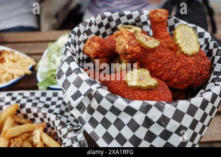 Primo piano di un succulento cesto ripieno di croccanti pezzi di pollo fritto, condito con sottaceti a fette. Foto Stock