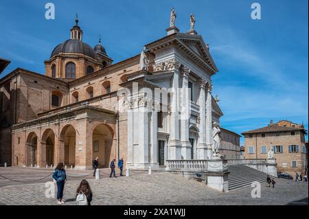 Una bella donna posa di fronte ad un edificio bianco della città in provincia di Pesaro e Urbino Foto Stock