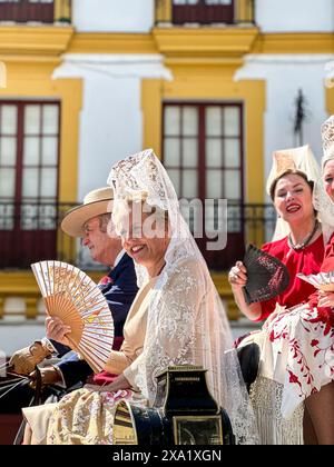 Donne in abiti tradizionali di flamenco su una carrozza trainata da cavalli alla Feria de Abril, nota anche come la Fiera di Siviglia Foto Stock