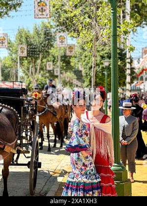 Donne in abiti tradizionali di flamenco su una carrozza trainata da cavalli alla Feria de Abril, nota anche come la Fiera di Siviglia Foto Stock