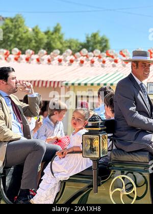 Donne in abiti tradizionali di flamenco su una carrozza trainata da cavalli alla Feria de Abril, nota anche come la Fiera di Siviglia Foto Stock