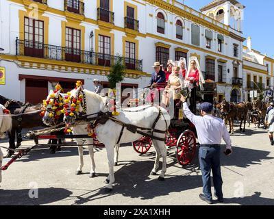 Donne in abiti tradizionali di flamenco su una carrozza trainata da cavalli alla Feria de Abril, nota anche come la Fiera di Siviglia Foto Stock