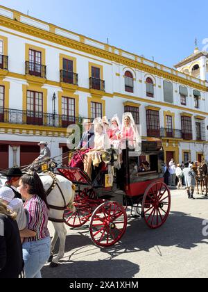 Donne in abiti tradizionali di flamenco su una carrozza trainata da cavalli alla Feria de Abril, nota anche come la Fiera di Siviglia Foto Stock