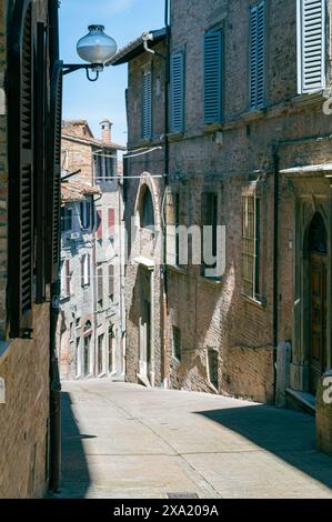 Un vicolo stretto circondato da edifici storici. Urbino, Italia Foto Stock