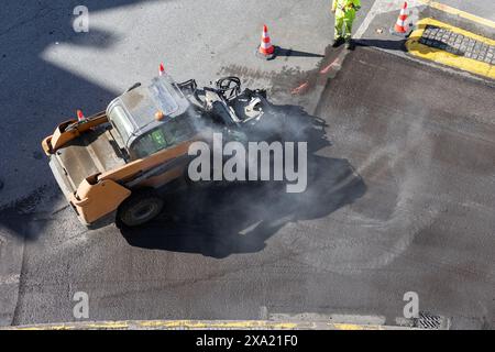 Vista aerea di una spazzatrice al lavoro durante il rinnovo dell'asfalto su una strada urbana Foto Stock