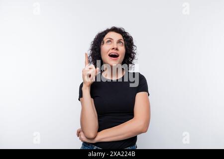 Donna europea riccia adulta che indossa una t-shirt nera ispirata a un'idea Foto Stock
