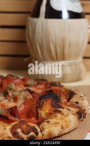 Una pizza appena sfornata su un tavolo con pomodori Foto Stock