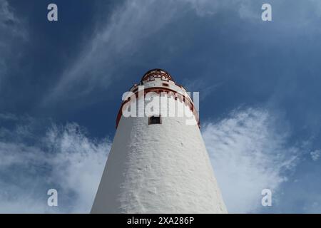 Una torre faro bianca e rossa si erge contro il cielo blu Foto Stock