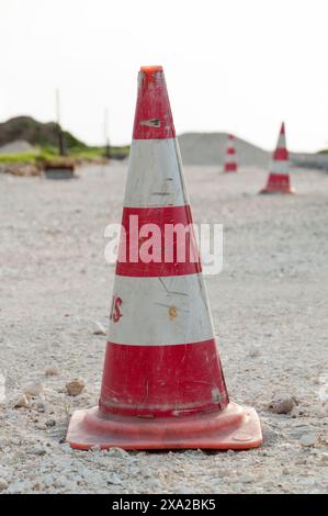 Un cono stradale rosso e bianco posto su strada sterrata Foto Stock