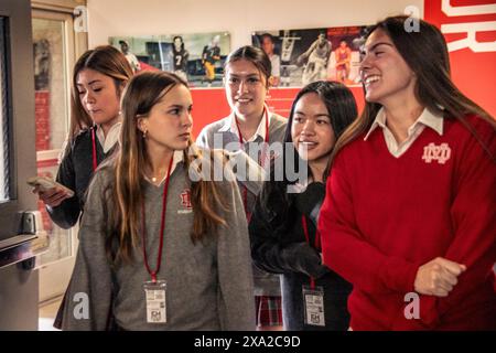 Le amiche adolescenti caucasiche e asiatiche in uniforme di una scuola cattolica della California meridionale interagiscono nel corridoio della scuola. Foto Stock