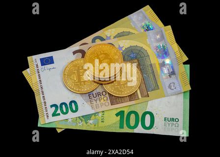 Monete in Bitcoin sulle banconote in euro in primo piano su sfondo scuro Foto Stock