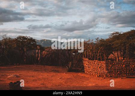 Questa accattivante fotografia cattura la bellezza serena di un villaggio sudafricano al tramonto, con capanne tradizionali e un cielo spettacolare, perfetto per tra Foto Stock