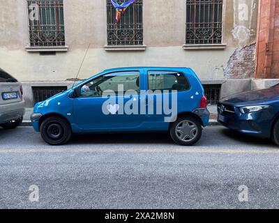 Cremona, Italia - 2 maggio 2024 una coppia gioiosa decora la sua auto blu con cuori bianchi per la celebrazione del matrimonio in una vivace strada cittadina, radiata Foto Stock