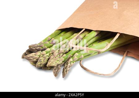 Un fascio di gambi di asparagi verdi freschi è disposto in modo ordinato in un sacchetto di carta marrone, ben visibile su sfondo bianco. Foto Stock