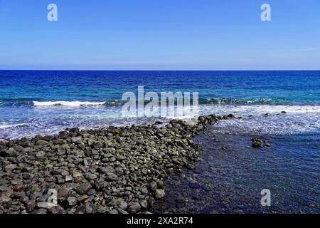 Spiaggia vulcanica nera a Candelaria, Tenerife, Isole Canarie, Spagna, Europa, costa rocciosa con onde dolci e cielo azzurro Foto Stock