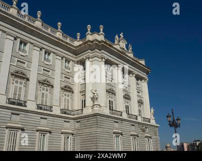 Grande edificio storico con sculture, balconi e facciate ornate sotto un cielo blu profondo, Madrid, Spagna Foto Stock