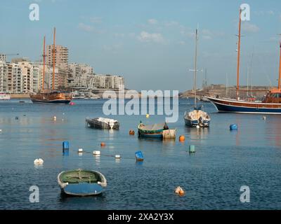 Barche da pesca e yacht in un porto tranquillo con una città sullo sfondo sotto un cielo limpido, porto naturale sul Mar Mediterraneo con storia Foto Stock