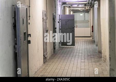 Corridoio in una prigione con porte in metallo e pavimento piastrellato. Atmosfera cupa e deserta, Berlin-Hohenschoenhausen Memorial, ex quartier generale Foto Stock