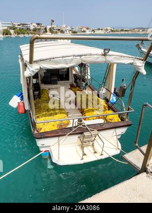 Barca da pesca ormeggiata al muro della banchina nel porto di Kokkinos Pyrgos, reti da pesca gialle a bordo, Kokkinos Pyrgos, Creta, Grecia Foto Stock