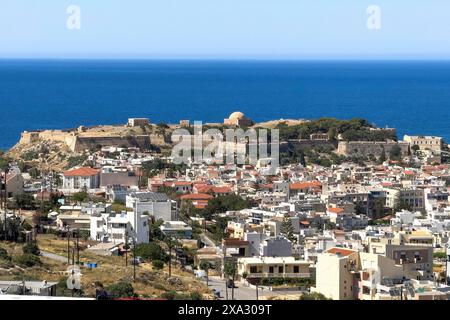 Vista dalla posizione elevata sui tetti della città di Rethymno sulle mura della fortezza e sulle rovine della fortezza storica Fortetza Fortezza di Rethymno costruita da Foto Stock