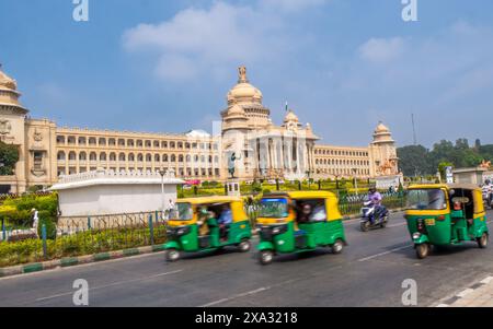 Bangalore, INDIA - 12 dicembre 2024: Auto Rickshaw, trasporto pubblico molto usato che passa vicino all'edificio Vidhana Soudha Foto Stock