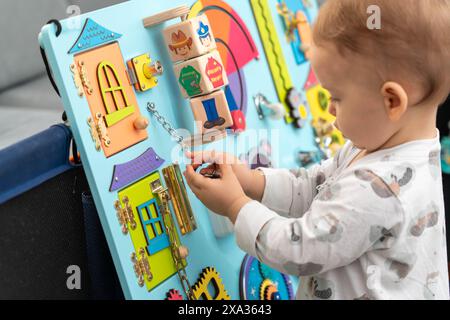 Bambino che tiene una chiave su una catena mentre gioca con un tabellone occupato Foto Stock