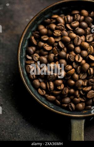 Chicchi di caffè tostati interi in una ciotola rustica Foto Stock