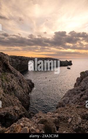 Tramonto a Pont d'en Gil, sull'isola di Minorca. Un arco naturale sul mare, popolare per ammirare il tramonto e scattare foto della natura. Isole Baleari Foto Stock