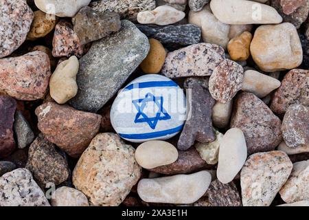 La bandiera israeliana ha dipinto la roccia. Pietra dipinta a mano con Magen David tra le altre rocce sulla spiaggia di ciottoli Foto Stock