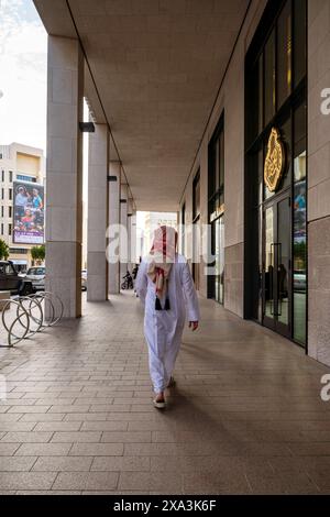 Msheireb nel centro di doha, qatar. Uomini arabi che camminano nel centro di Msheireb a doha vista dal retro Foto Stock