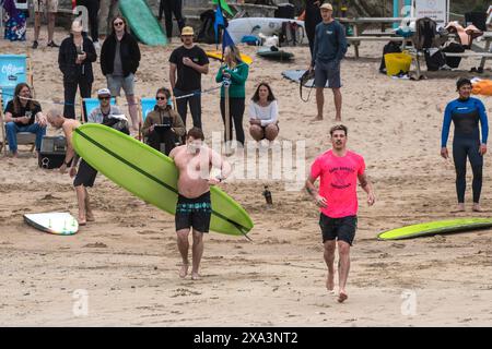 I surfisti che corrono fino al mare per gareggiare nella gara di surf Sand Bandit Showdown al GT Western Great Western Beach di Newquay in Cornovaglia nel Foto Stock