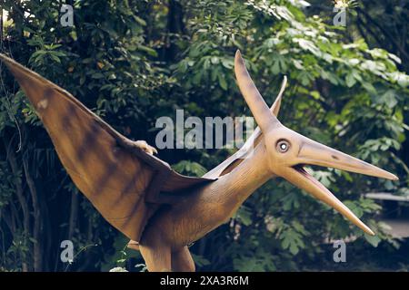 Parco dei dinosauri in uno spazio aperto. Un giardino di dinosauri con predatori ed erbivori del periodo giurassico. Uno pterodattilo con spazio da copiare. Foto di alta qualità Foto Stock