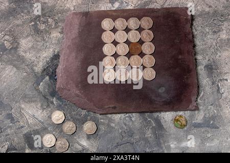 Un pezzo arrugginito di 50 pence inglese trovato in un giardino disposto con monete brillanti che mostrano la testa della defunta regina Elisabetta. Foto Stock