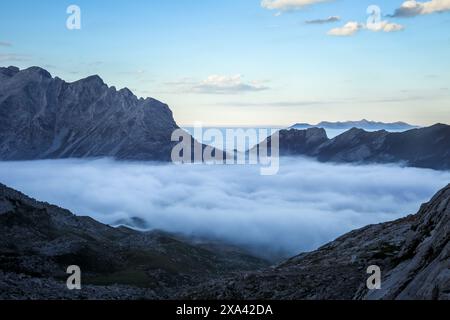 Splendida vista, paesaggio montano, Picos de Europa, Spagna, vette immerse nelle nuvole. Sopra le nuvole, al crepuscolo. Cielo blu Foto Stock