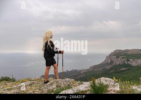 Una donna si trova su una collina che si affaccia sull'oceano Foto Stock