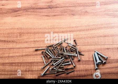 Viti, dadi, rondelle, chiave a L, isolata su fondo in legno. Foto Stock