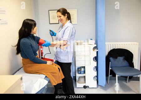 Infermiere che controlla la pressione sanguigna del paziente in clinica Foto Stock