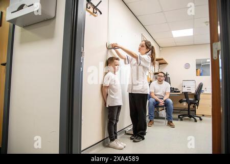 Bambino misurato durante un controllo medico come osserva il padre. Foto Stock