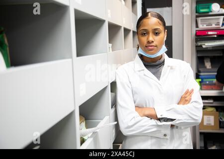 Professionista sanitario sicuro in un camice da laboratorio in piedi con le braccia incrociate. Foto Stock