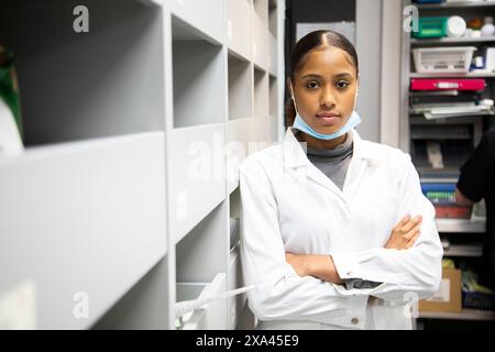Professionista sanitario sicuro in un camice da laboratorio in piedi con le braccia incrociate. Foto Stock